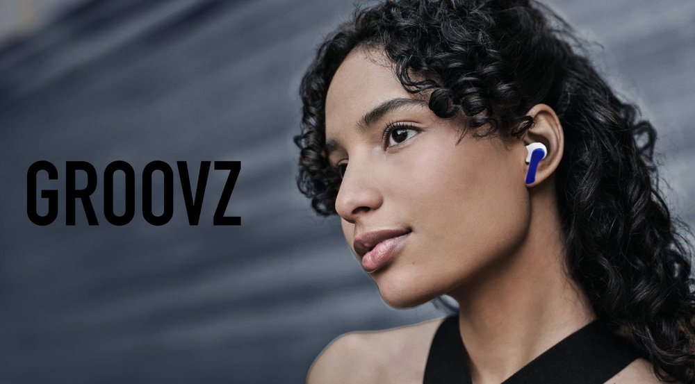 a girl with curly hair wearing blue and white earbuds looks pensive. "GROOVZ" is displayed in black text on the left.