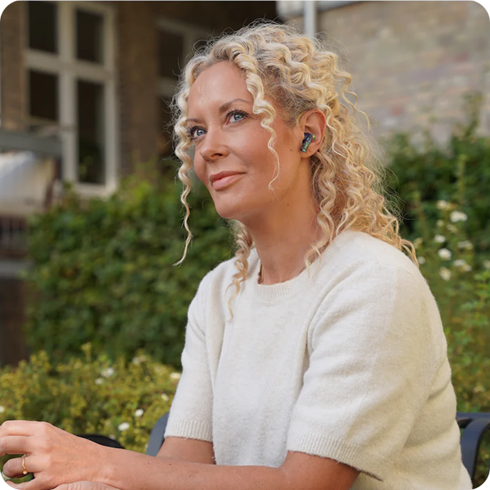 Woman Wearing Groovz True Wireless Earbuds in Floral Design – Relaxing Outdoors with Casual Style and Natural Surroundings